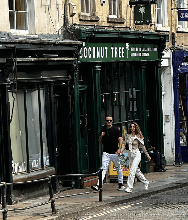 A couple walking hand-in-hand down a historic city street in Bath